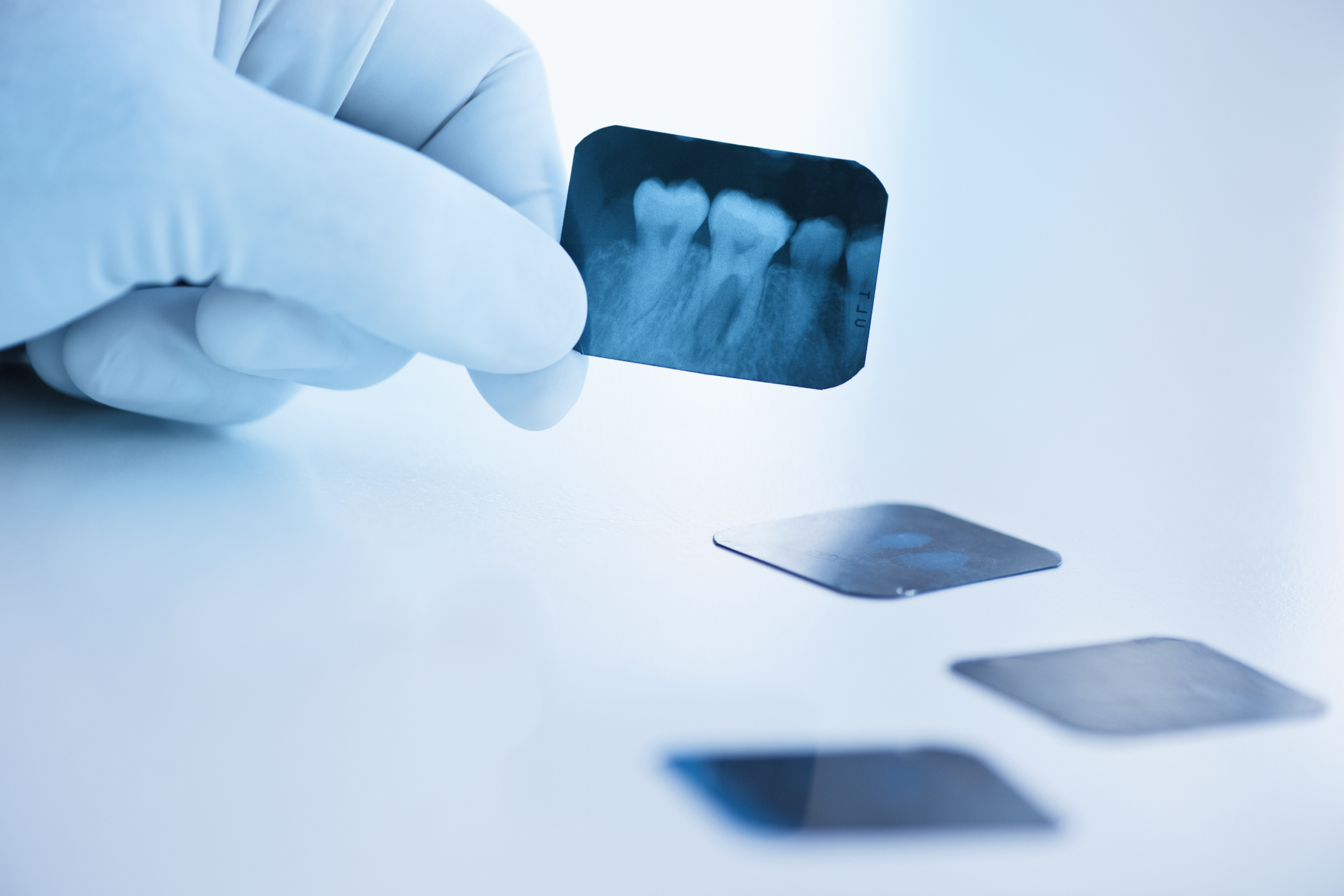 Dra. Adriana revisando una radiografía dental con guante de látex